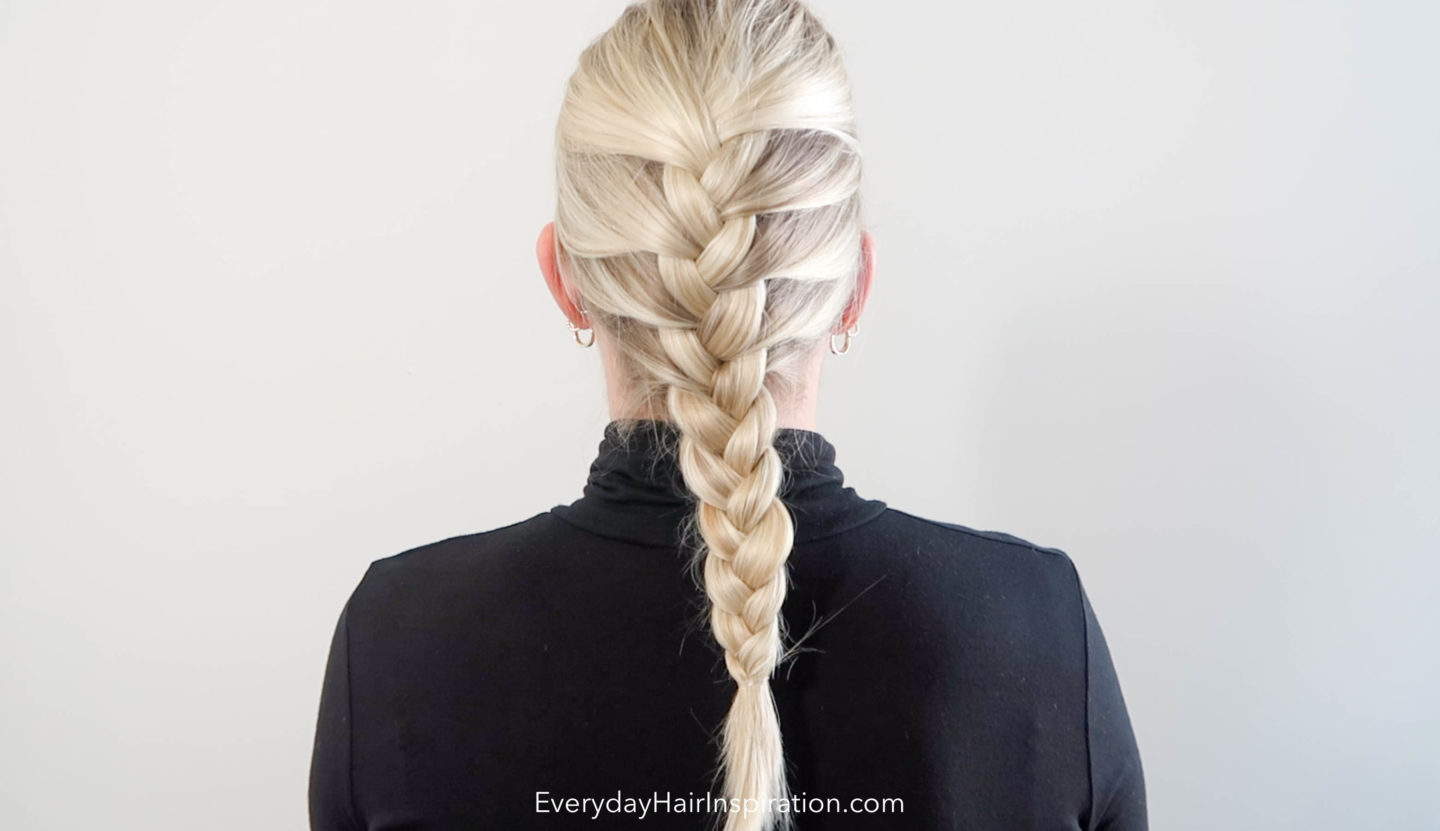 Woman sitting with the back to the camera, the hair is braided in a french braid 